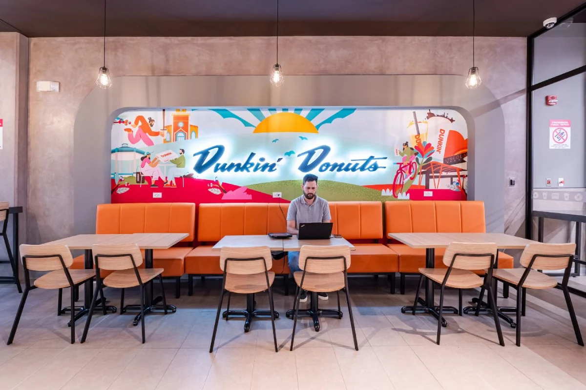 Dunkin Donuts - Custom banquette seating with branded wall graphics and warm lighting - Contract Workplaces.webp